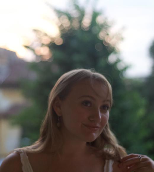 Person standing a posing for a picture. The background is blurred.