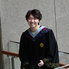 Student wearing their graduation gown and posing for a picture. 