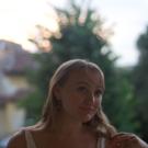 Person standing a posing for a picture. The background is blurred.